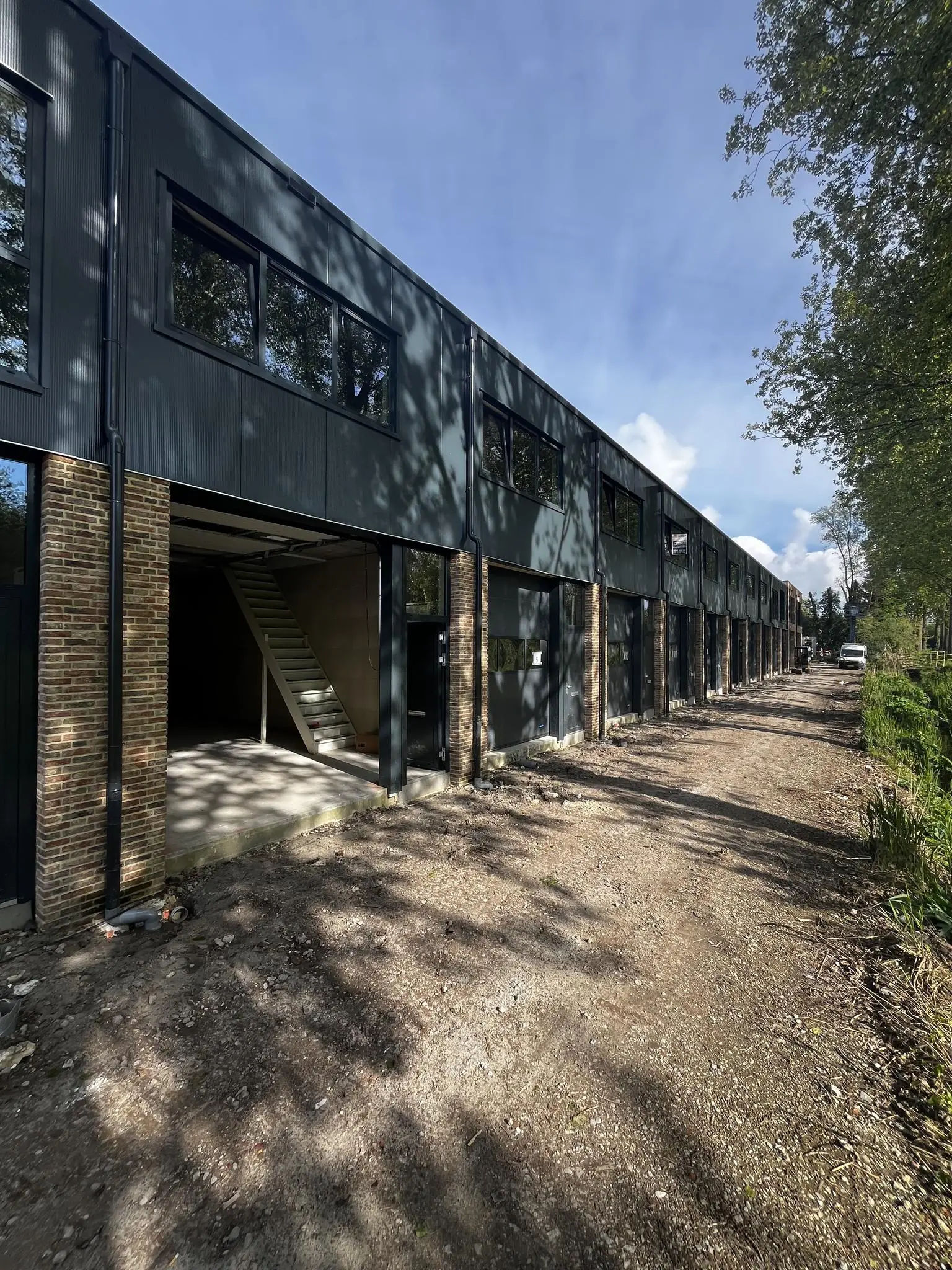 Nieuwbouw bedrijfsunits aan de Broekdijk West met open garage en trap in een onafgewerkte omgeving.
